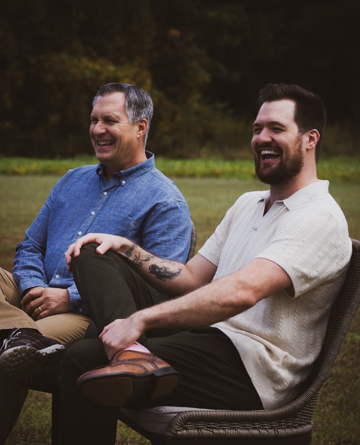Two men sharing a big laugh in wicker chairs